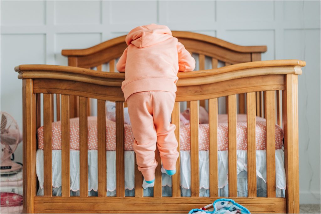 kid climbing on his sister's crib to peek at her
