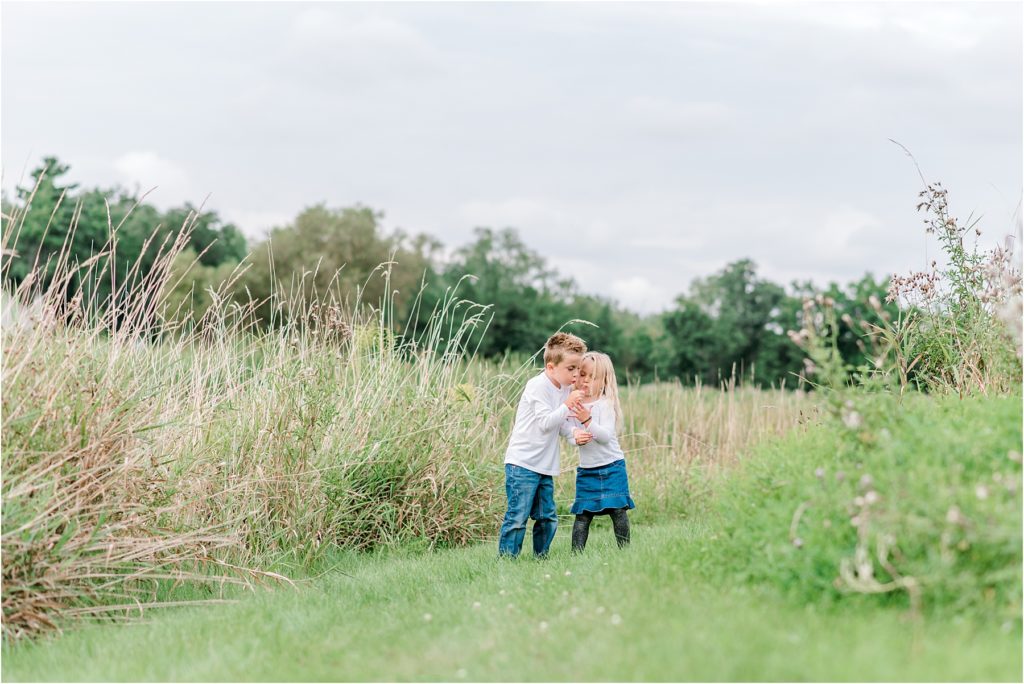 Children in a field blowing on a flower, family photo session