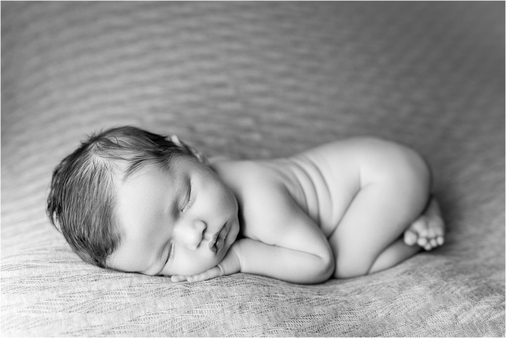 Black and white photo of newborn laying on their tummy. Newborn portrait session.