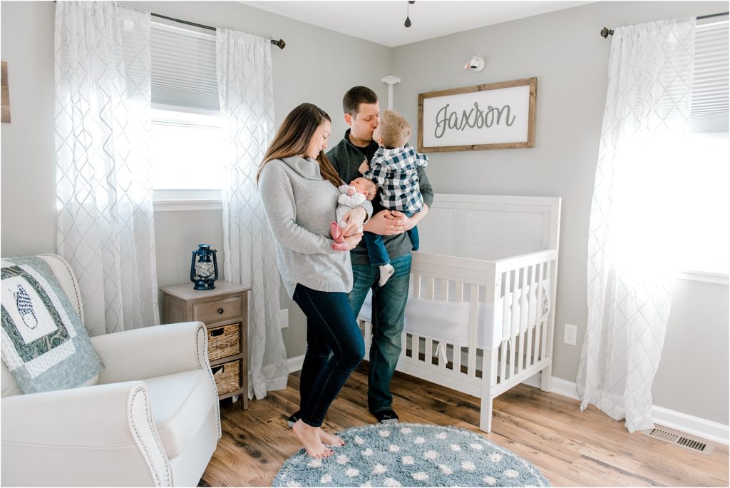 In-Home lifestyle newborn session photograph of a family standing in the baby's nursery.