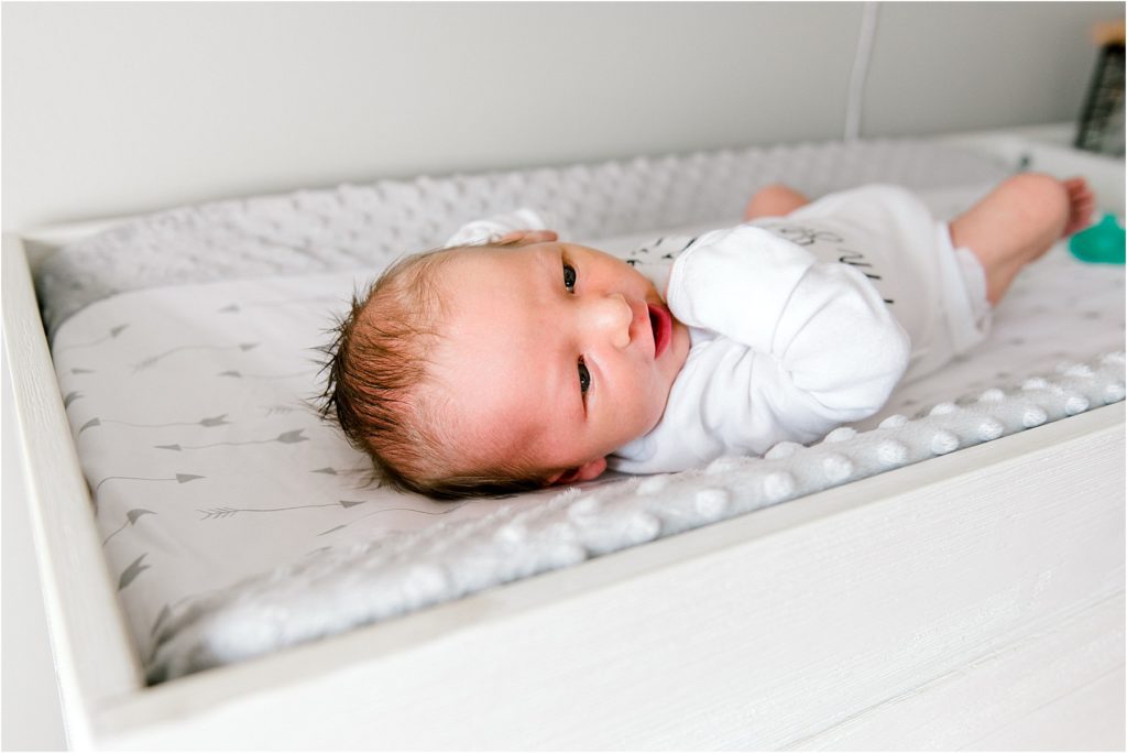 Newborn baby in a white onesie smiling