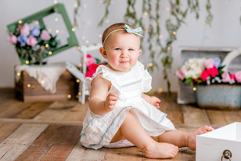 Baby in front of a floral backdrop.