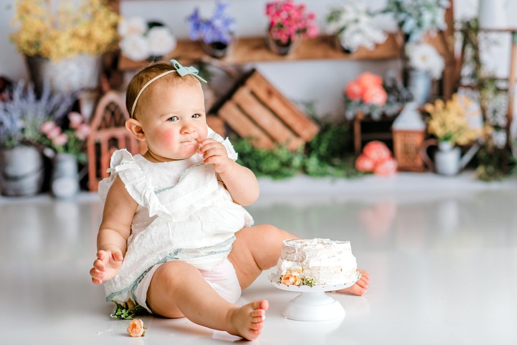 Baby eating cake at her first birthday floral cake smash photo shoot.