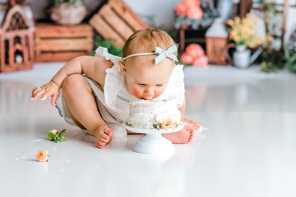 Baby eating cake at her first birthday floral cake smash photo shoot.
