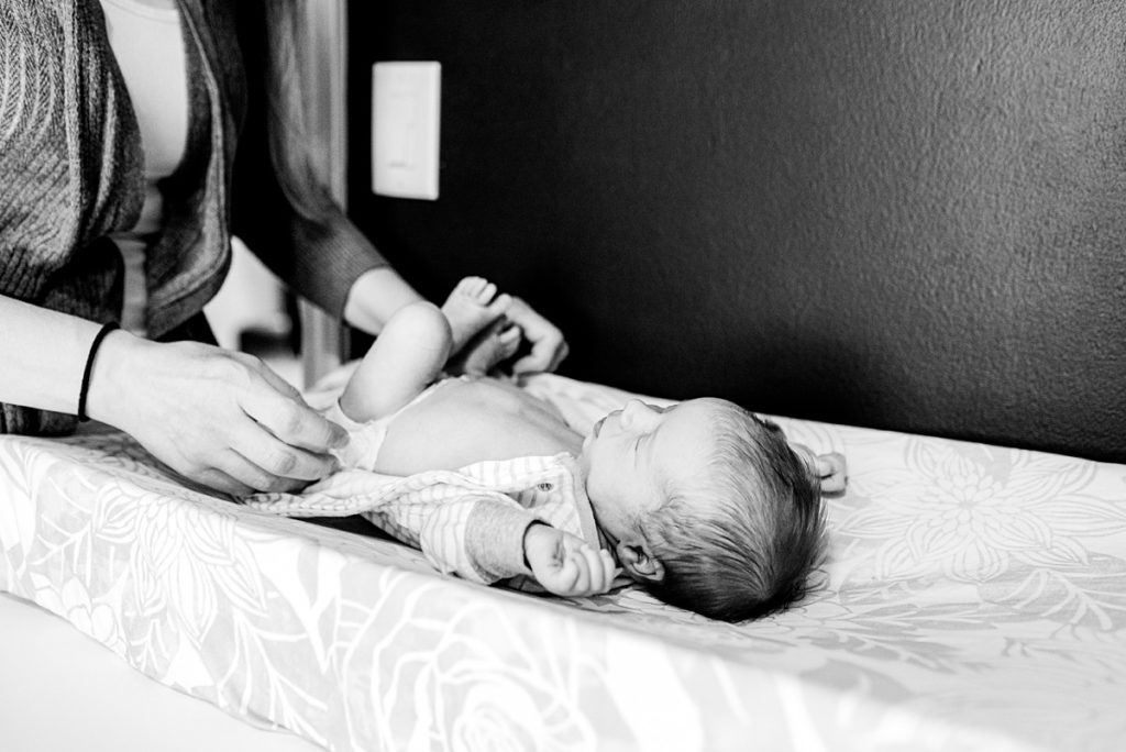 Howell Mi Photographer, lifestyle newborn photo session. Baby stretching on changing pad.