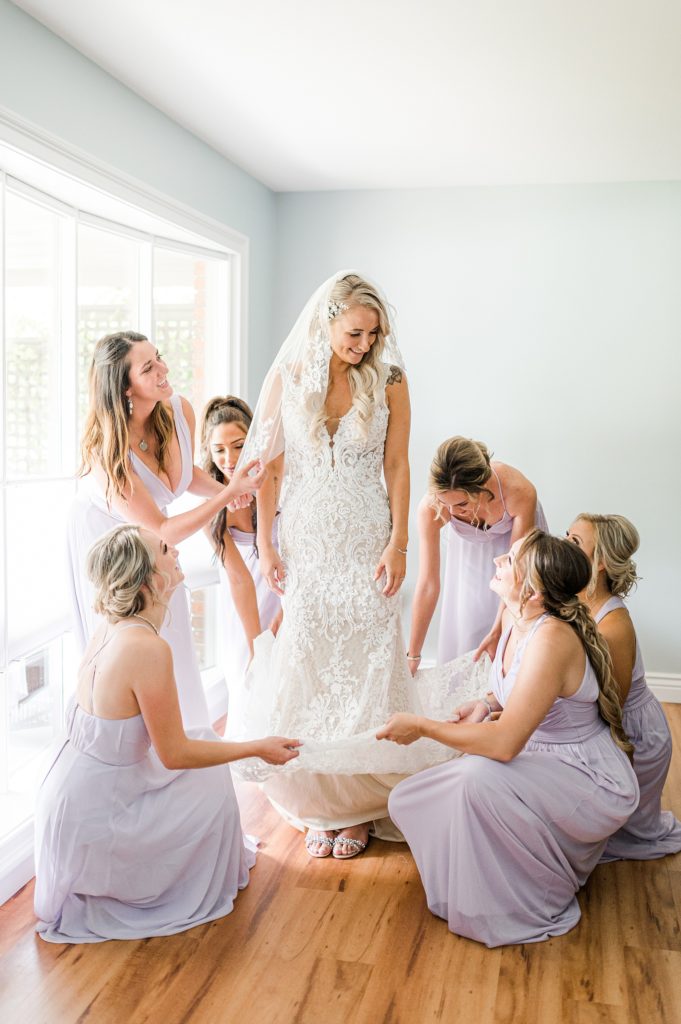Bridesmaids surrounding bride fluffing her dress