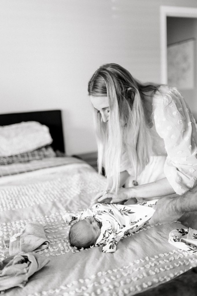 Mom dressing her newborn baby, photo taken by an Ann Arbor Newborn Photographer