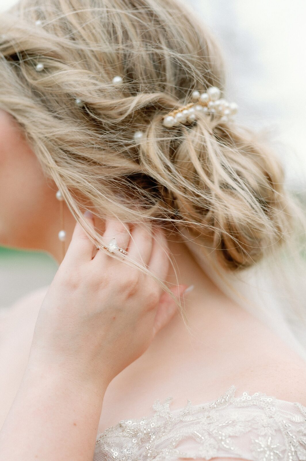A close up detail photo of a bride's ring as she fixes her hair.