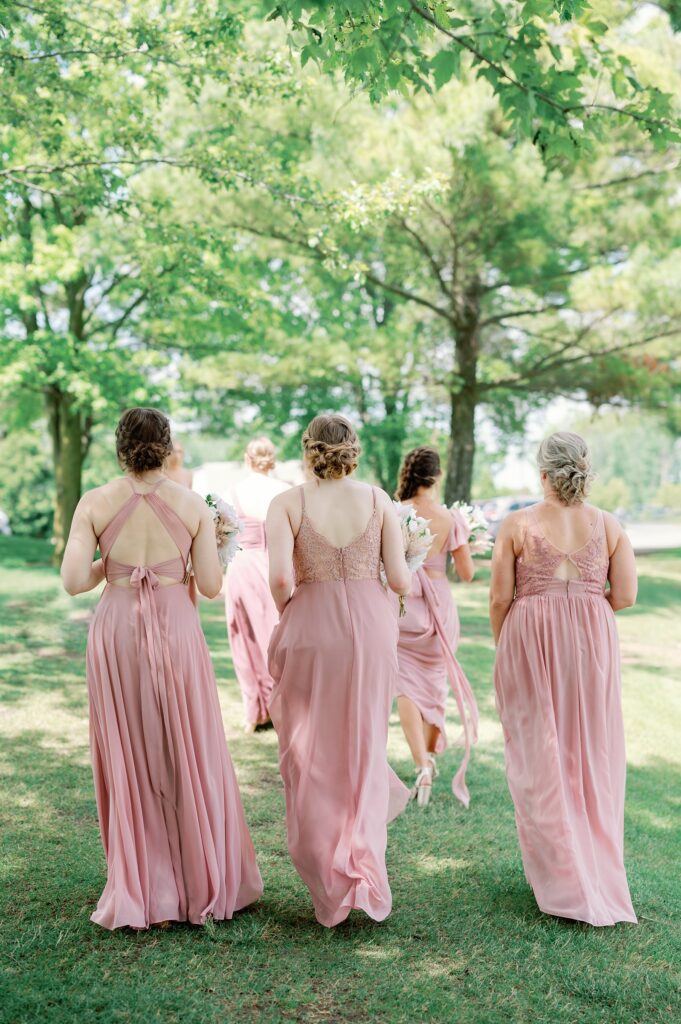 Bridesmaids in pink gowns walking away from the camera