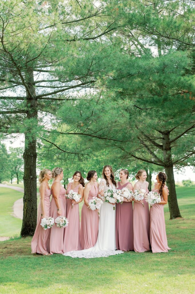 Bride with her bridesmaids, standing in a line giggling.