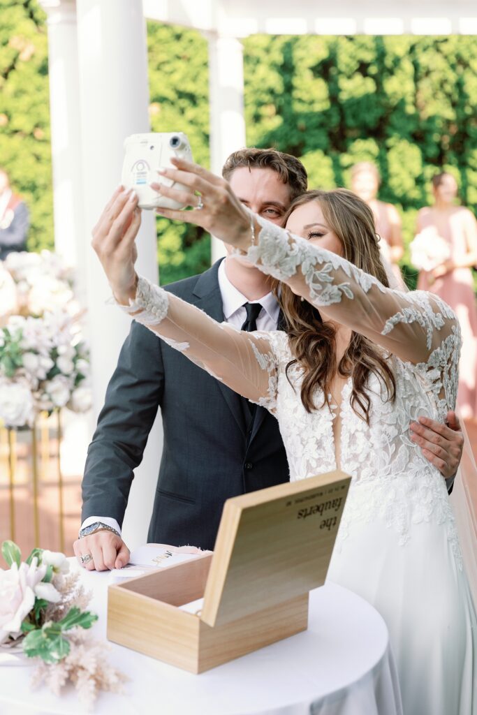 Bride and groom taking a selfie with a polaroid camera.