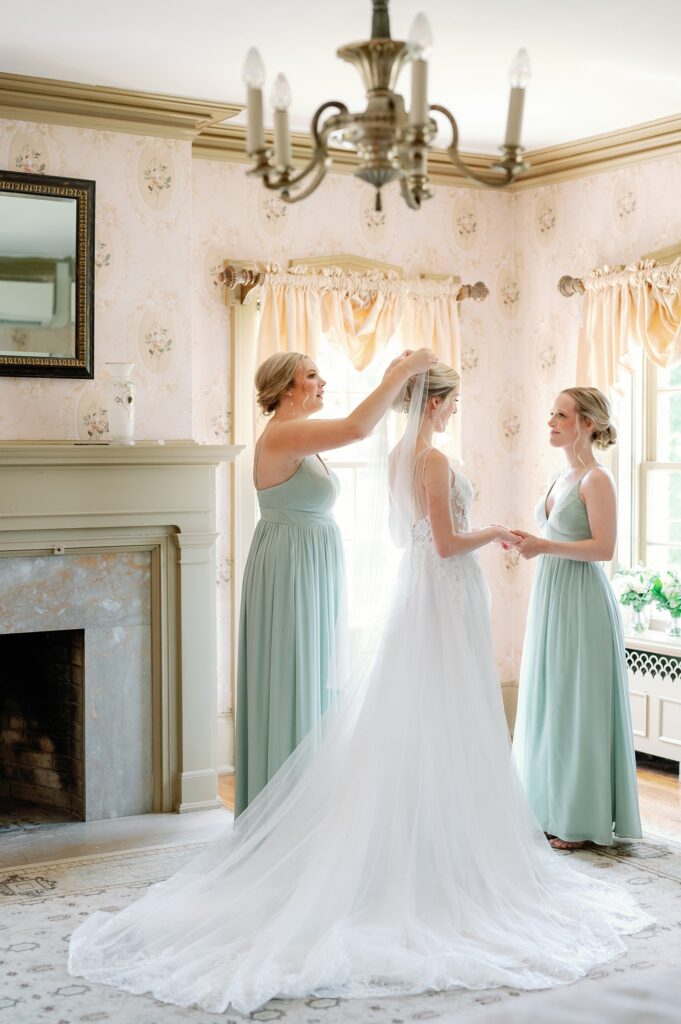 Bridesmaids having a special moment with bride as they pin her veil in her hair.