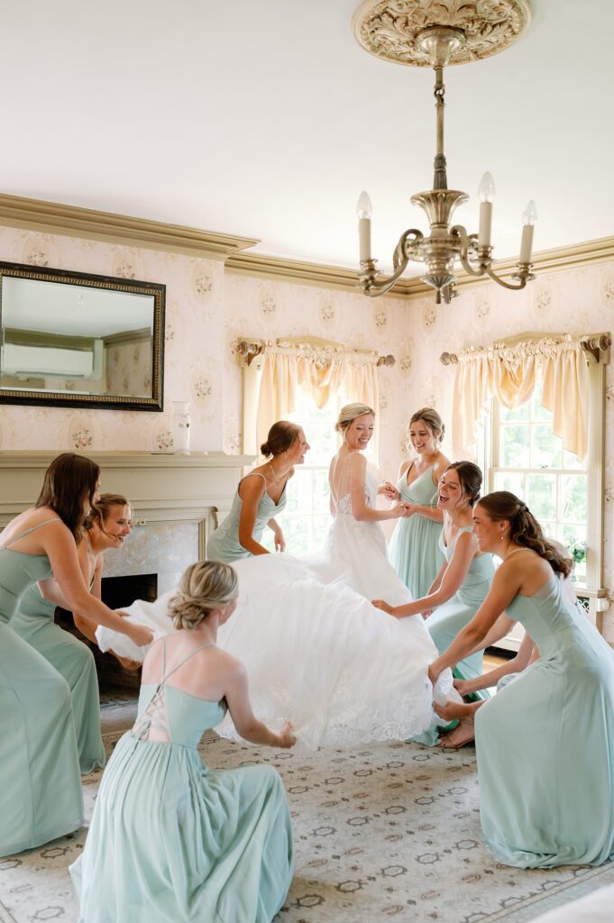 Bridesmaids surrounding bride as they primp her while getting ready for the wedding ceremony