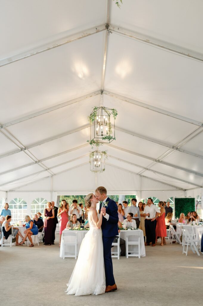 bride and groom share their first dance under the white wedding reception tent at the felt mansion outside.