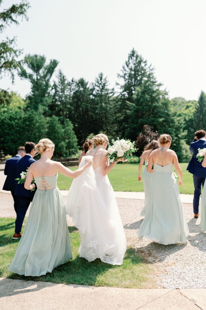 bridesmaids walking while holding the brides gown