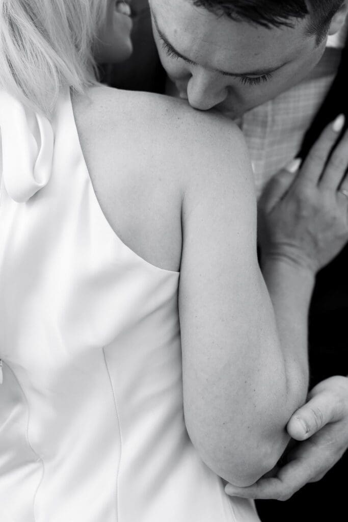 Black and white close-up of a couple embracing, her hand resting on his shoulder