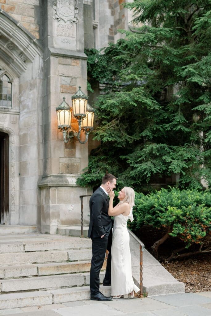 A couple standing together beneath the Law Quad's stone archway and lantern lights