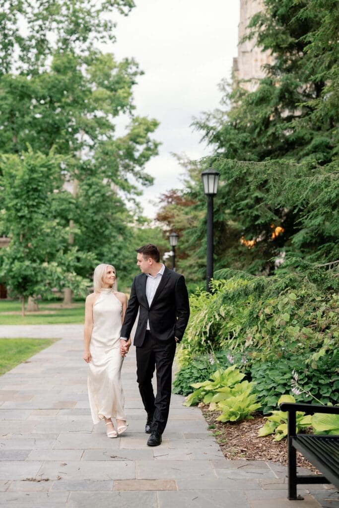 A couple walking hand in hand along a lantern-lined path, Ann Arbor engagement photography