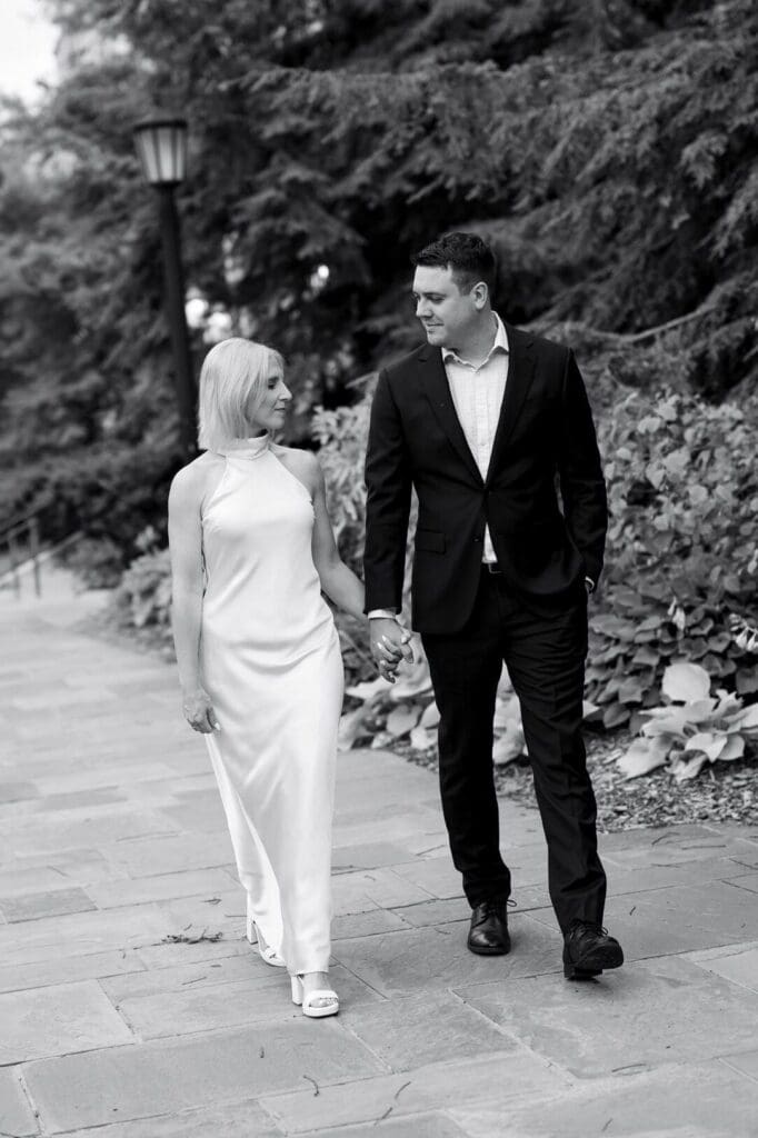 Black and white photo of a couple walking together, looking at each other and smiling, at the Law Quad