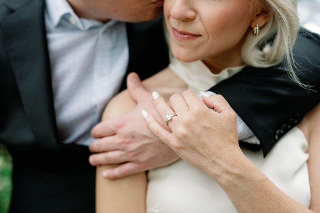 Close-up detail of an engagement ring as a couple embraces